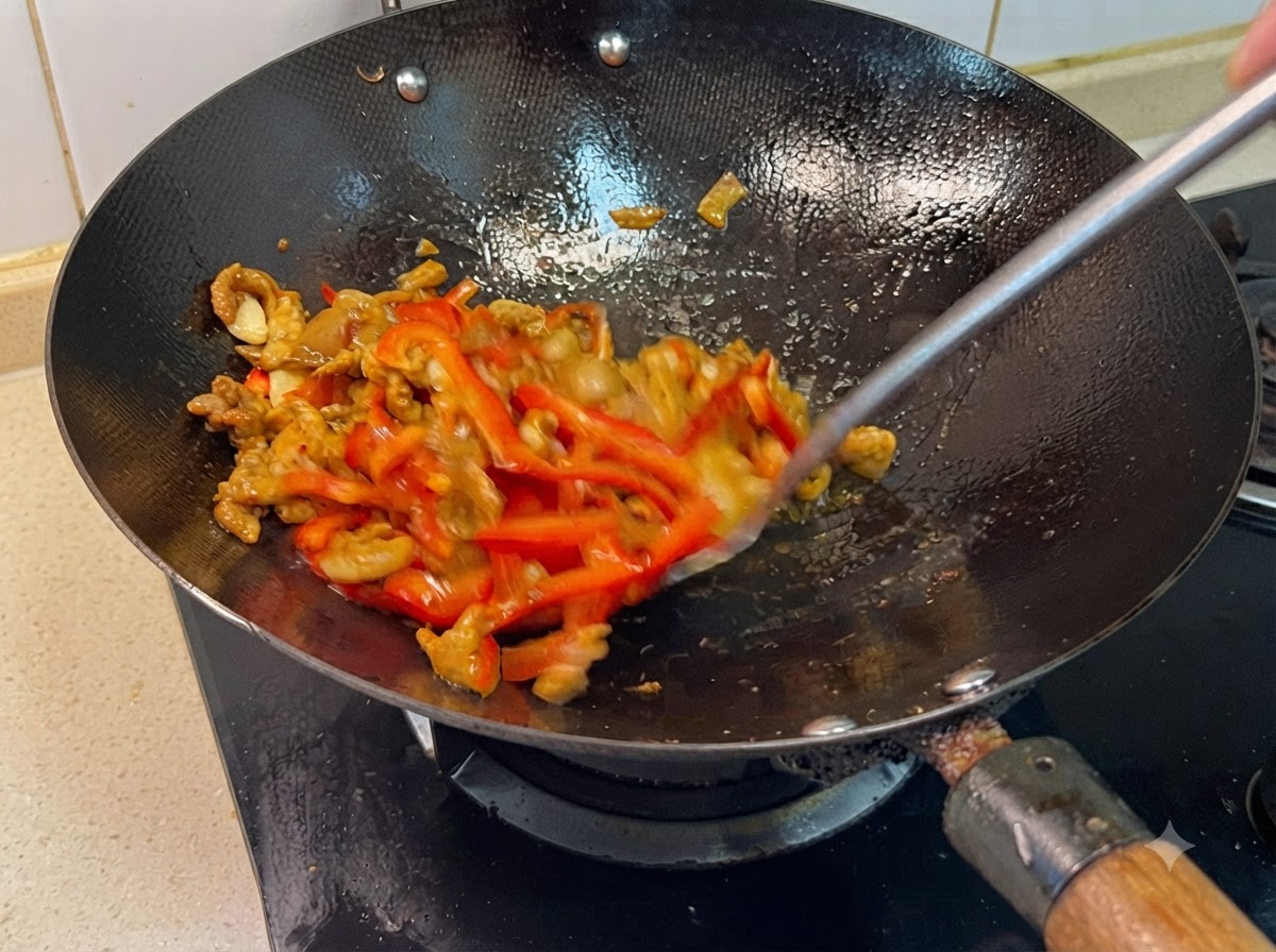 Une spatule mélangeant les poivrons rouges et le porc dans un wok tandis que les assaisonnements sont incorporés.
