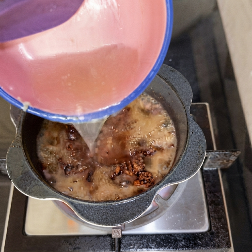 Du liquide versé dun bol rose dans la casserole de sauce à la viande.