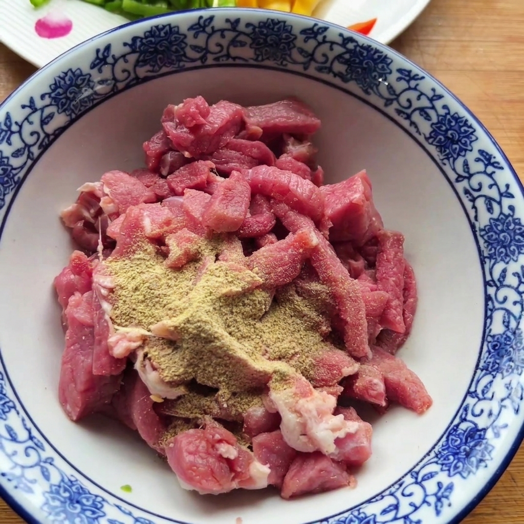 Morceaux de bœuf cru dans un bol à motifs surmontés dépices en poudre sèches.