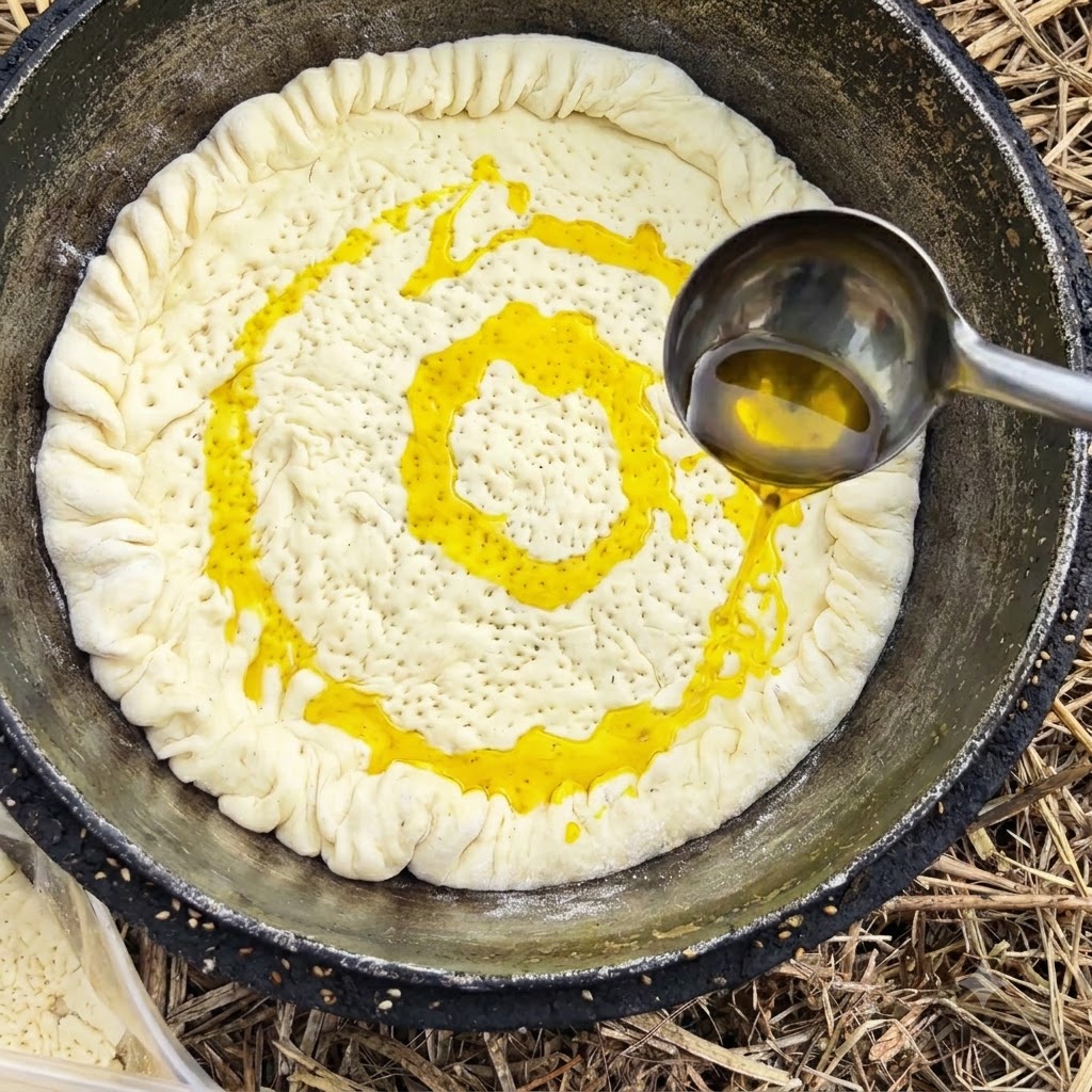 Une louche en métal versant de lhuile de cuisson jaune sur une croûte de pâte à lintérieur dun pot.