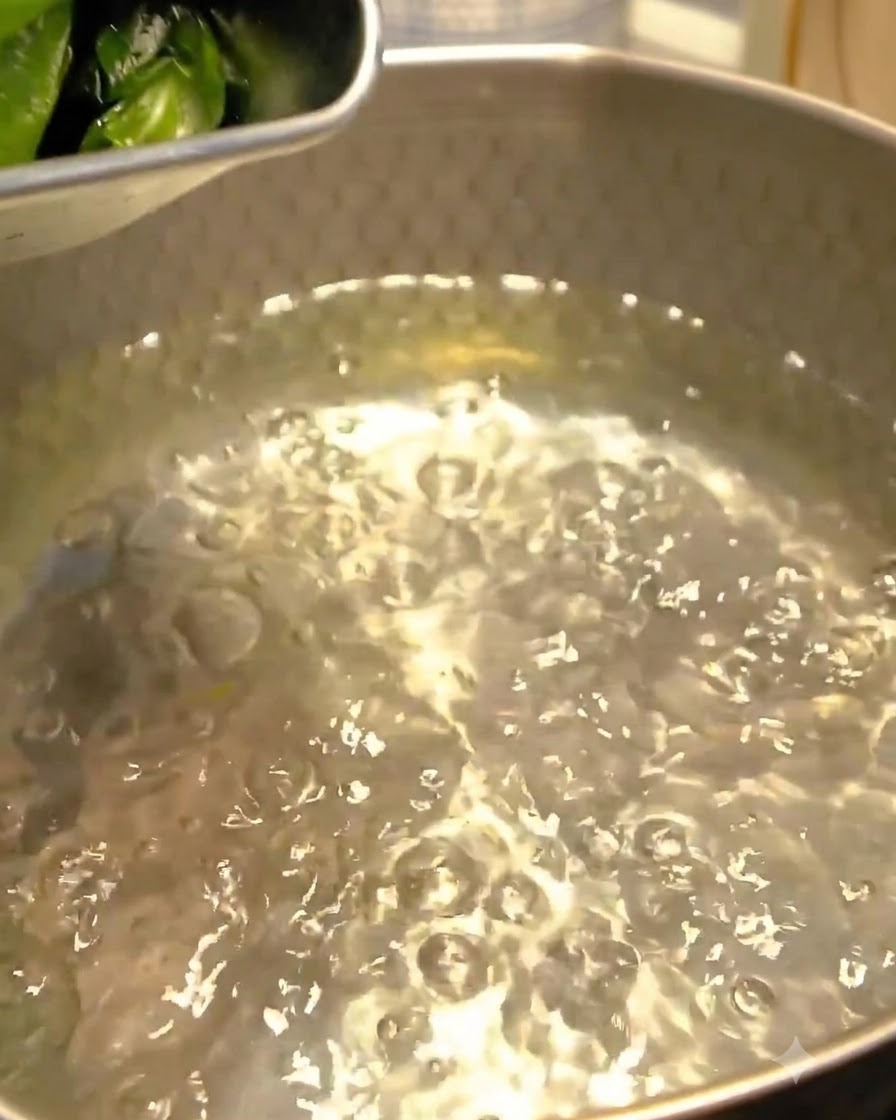 Des algues wakame jetées dans de leau bouillonnante dans une casserole en métal.