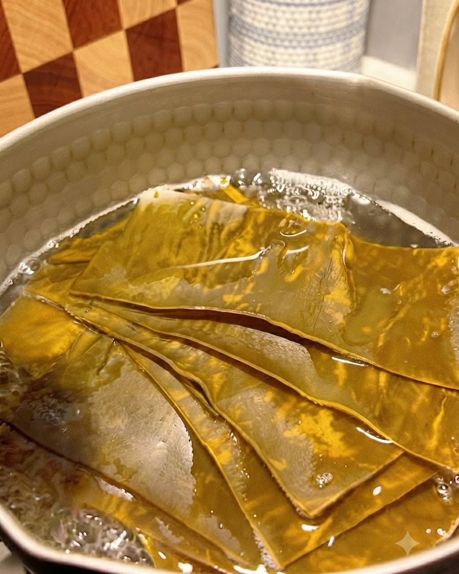 Des flocons de bonite ajoutés dans le bouillon de kombu frémissant dans une casserole en métal.